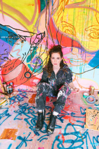 Multi-Material-Künstlerin Larissa Kerner in ihrem Zuhause-Atelier in Hamburg-Rahlstedt mit ihren liebsten Arbeitswerkstoffen wie Leinwand, Acryl-Farben, Spraydosen und Gaffer-Tape-Bändern: „Die Vibes in Rothenburgsort sind ganz anders als in der HafenCity, der die Seele fehlt. Die Häuserwände erzählen keine Geschichten.“ © Sarah Rechtbauer