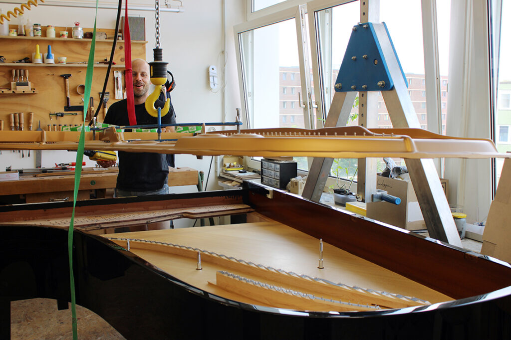 Klavierbauer Stefan Bammann senkt eine Gussplatte in den aufgearbeiteten Steinway-Flügel ab: „Wir erhalten den Klangkörper und verbinden ihn mit moderner Technik.“	 © Dagmar leischow