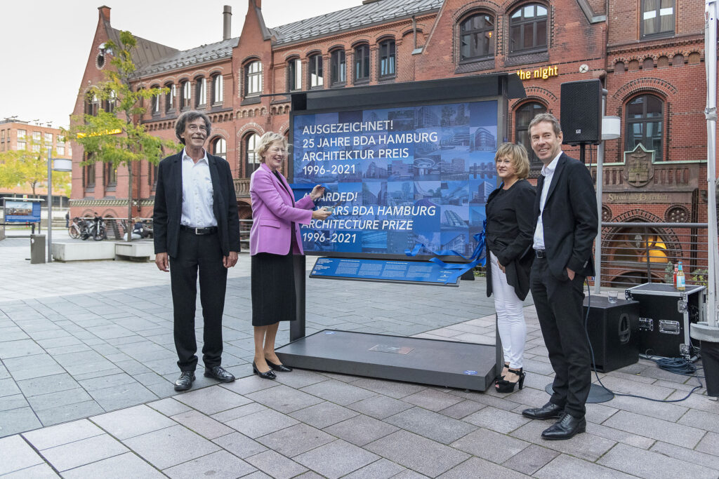 Feierliche Eröffnung der Open-Art-Ausstellung „Ausgezeichnet! 25 Jahre BDA Hamburg Architektur Preis 1996-2021“ auf dem Marktplatz des Überseeboulevards vorm Alten Hafenamt – mit dem früheren Oberbaudirektor und Festredner Prof. Jörn Walter, Stadtplanungs- und Wohnensenatorin Dr. Dorothee Stapelfeldt und Quartiersmanagerin Überseequartier Nord Dr. Claudia Weise sowie Architekt Finn Warncke, 1. Vorsitzender BDA Hamburg (v.l.n.r.): „Jeder der gezeigten Gewinnerbauten veranschaulicht nicht nur eindrücklich den architektonischen Ausdruck seiner Zeit, sondern ist auch beispiel- gebend für die vorrangigen Bauaufgaben seiner Entstehungszeit.“ © Julia Knop | Überseequartier Nord