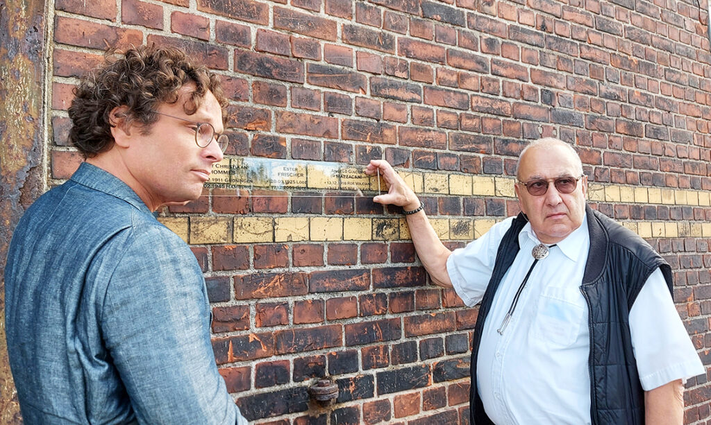 Erinnern I: Floris Hommes (li.), Vorsitzender Lagerhaus G Heritage Foundation und Mario Mazzacani, Sohn von Angelo Giacomo Mazzacani, der am Dessauer Ufer traumatisierten wurde. Auf der Acrylgedenkplakette sind die Namen der Angehörigen aufgebracht. © Matthias Schinck